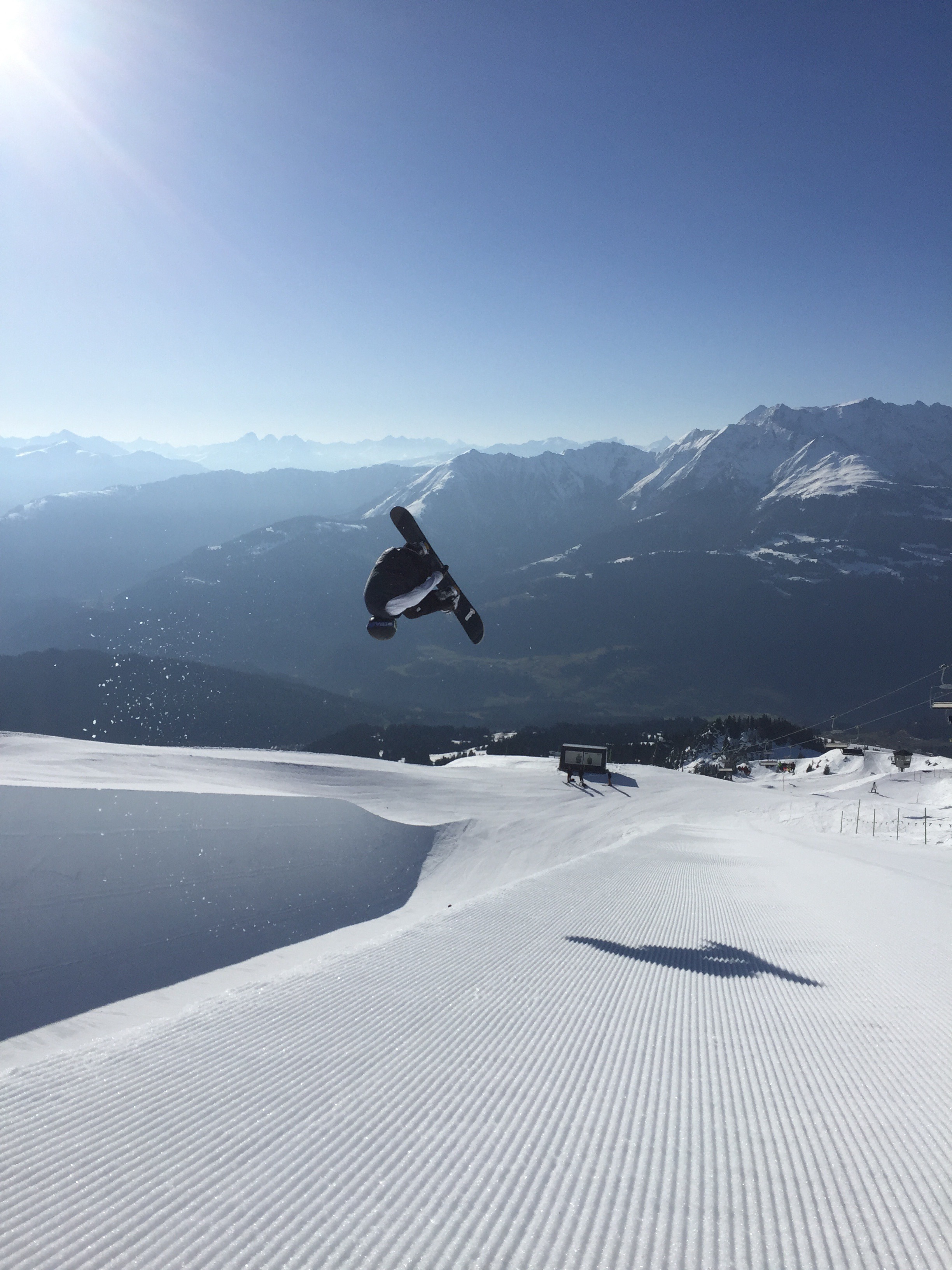 Snowboarder Marco Hauri mit einem Grab über einem Kicker vor Alpenpanorama